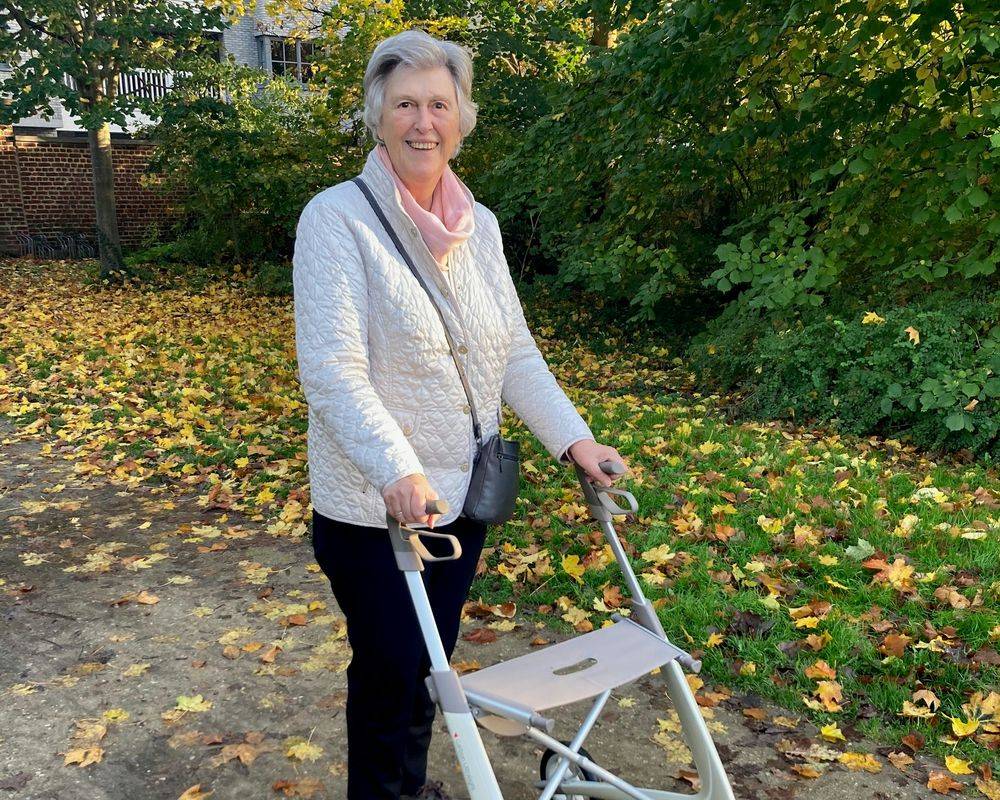 An older woman standing with a wheeled walker